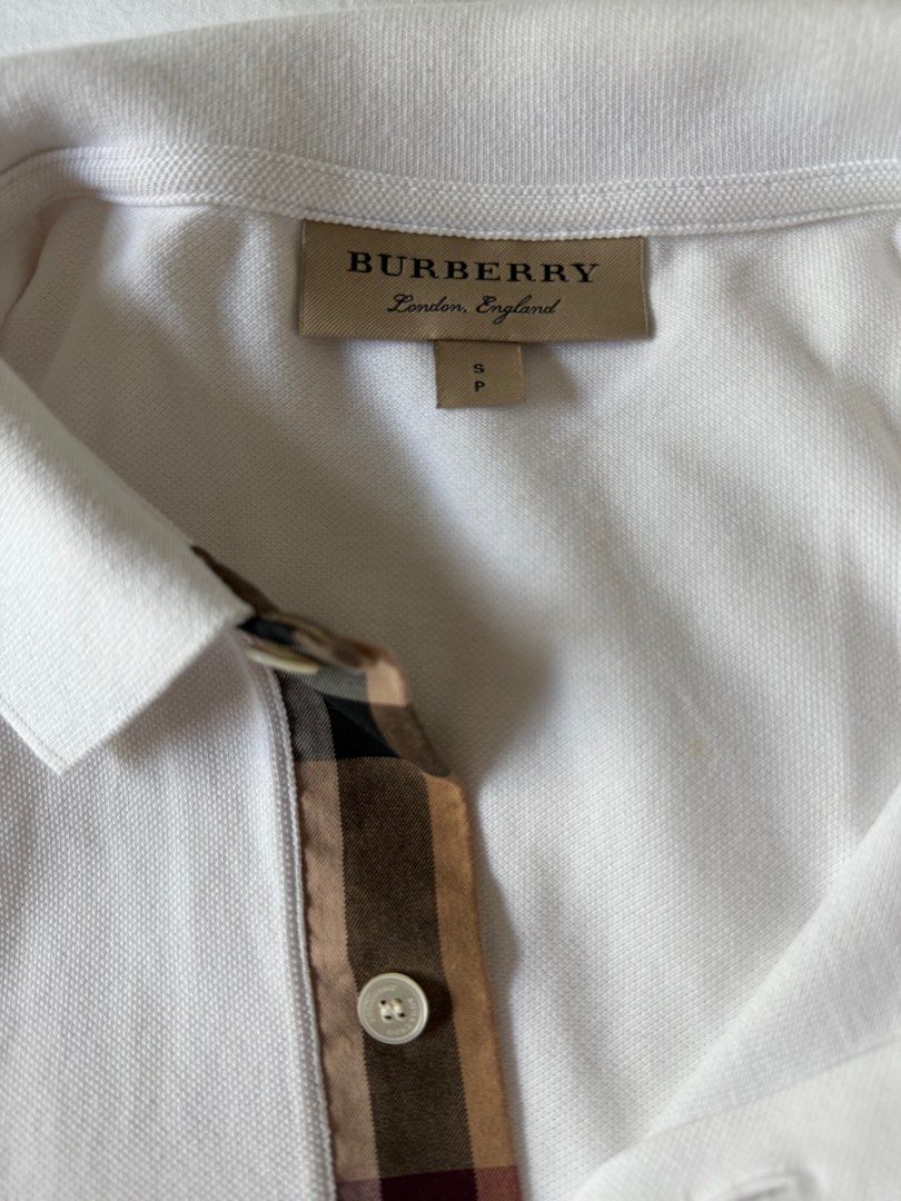 Burberry White Polo Shirt (Category: Tshirts & Polo Shirts ) located in Manila. Submitted by inob2024 (Listing ID 1405100077, Image 2). Description: White Burberry polo shirt with the brand logo on the chest. Features a classic collar and short sleeves. The shirt has a unique plaid pattern detail on the placket. Size S. Burberry polo shirt size S white and blue.