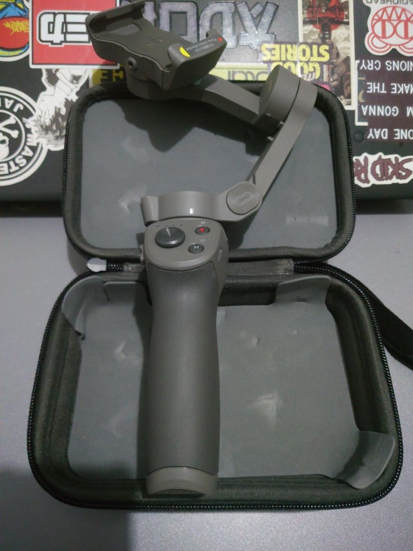 DJI Osmo Mobile Gimbal Stabilizer (Category: Gimbals & Stabilizers ) located in Mandaluyong City. Submitted by iamador (Listing ID 1405126375, Image 3). Description: - DJI Osmo Mobile gimbal stabilizer - Includes: gimbal, carrying case, and soft pouch - Color: Gray - Condition: Good - Features control buttons on the handle - Carrying case and soft pouch feature the Osmo logo.