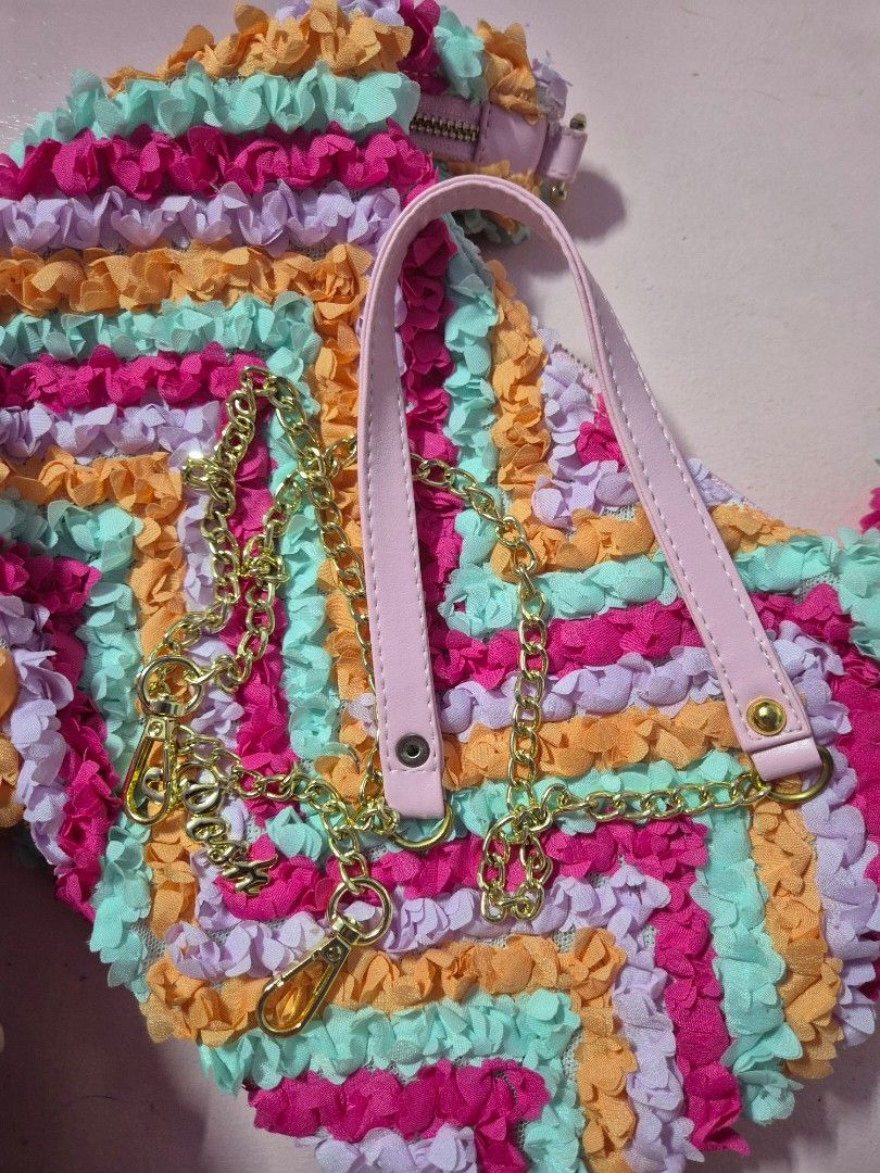 Posh Ruffled Handbag with Chain Strap from Thailand (Category: Luxury Bags & Wallets) located in Manila. Submitted by bangtanroxyy (Listing ID 1405039583, Image 2). Description: - Brand new colorful handbag - Unique ruffled design in pink, orange, purple, and blue - Includes a detachable pink and gold chain strap - Secure zipper closure - Gold-toned Posh logo - Comes in original packaging - From Thailand - Posh is a Thailand brand.