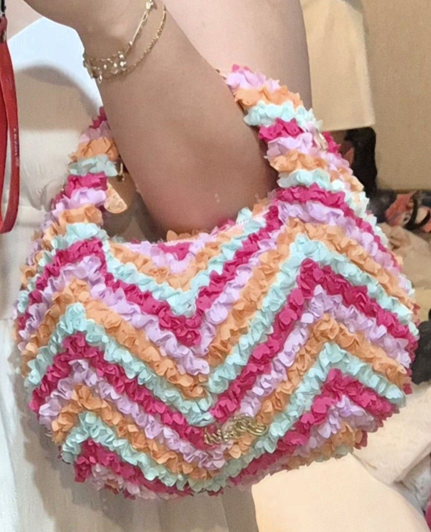 Posh Ruffled Handbag with Chain Strap from Thailand (Category: Luxury Bags & Wallets) located in Manila. Submitted by bangtanroxyy (Listing ID 1405039583, Image 1). Description: - Brand new colorful handbag - Unique ruffled design in pink, orange, purple, and blue - Includes a detachable pink and gold chain strap - Secure zipper closure - Gold-toned Posh logo - Comes in original packaging - From Thailand - Posh is a Thailand brand.