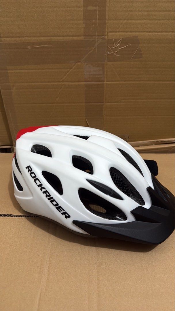 Rockrider MTB 500 Helmet (Category: Other Sports Equipment and Supplies) located in Taguig. Submitted by lalohan (Listing ID 1405002615, Image 1). Description: Rockrider MTB 500 helmet is designed for mountain biking. It features a white and black color scheme with multiple vents for airflow. The helmet has an adjustable strap system for a secure fit. The interior includes padding for comfort. The helmet is a size Teen and has a visor..