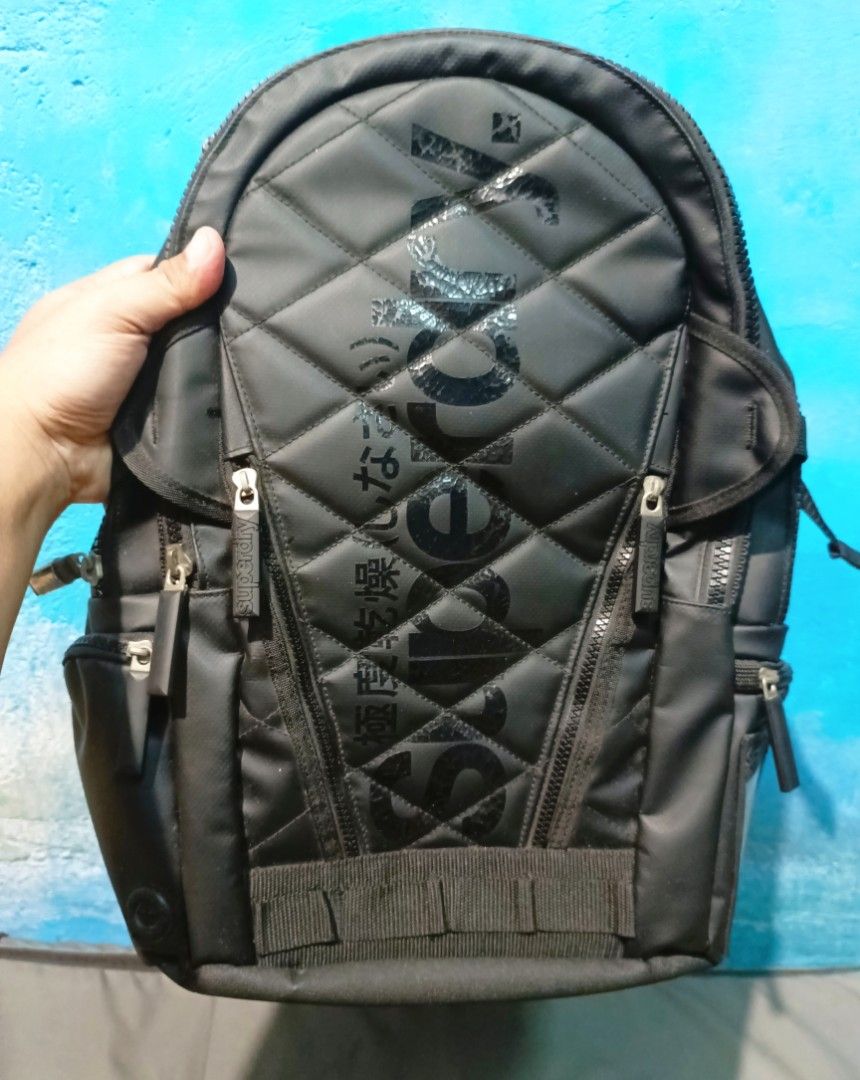 Superdry quilted Black Backpack authentic (Category: Backpacks) located in Manila. Submitted by welbern (Listing ID 1404994376, Image 3). Description: Minor scratches https://youtu.be/zo1DPgy9GIg?si=u45dYhibCb230IGL - Black Superdry backpack - Quilted front design - Multiple zippered compartments - Side pockets - Front pocket - Adjustable straps - Top handle - Superdry logo on front and back - Interior mesh pocket - Separate compartment.