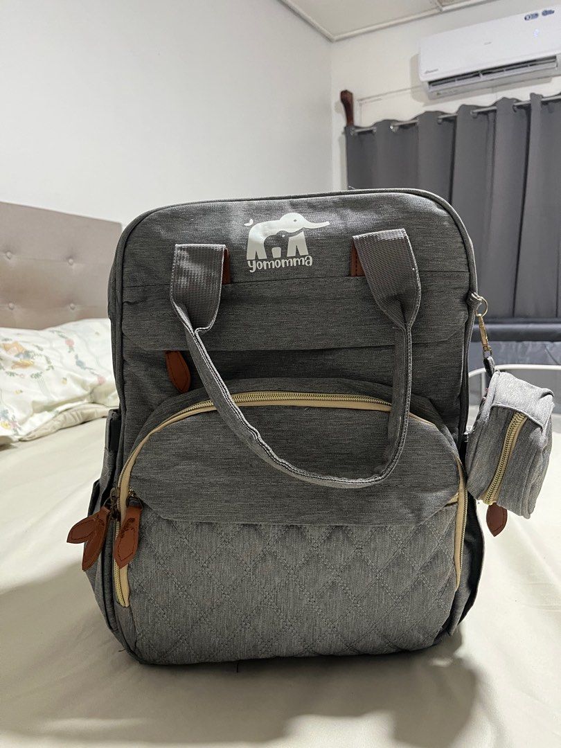 Yomomma Diaper Backpack Bag (Category: Diaper Bags & Wetbags) located in San Fernando. Submitted by akcd12 (Listing ID 1405059627, Image 2). Description: - Spacious main compartment - Multiple pockets for organization - Front quilted pocket - Side pockets - Detachable pouch - USB charging port - Includes changing pad - Stroller straps - Stylish gray with brown accents .