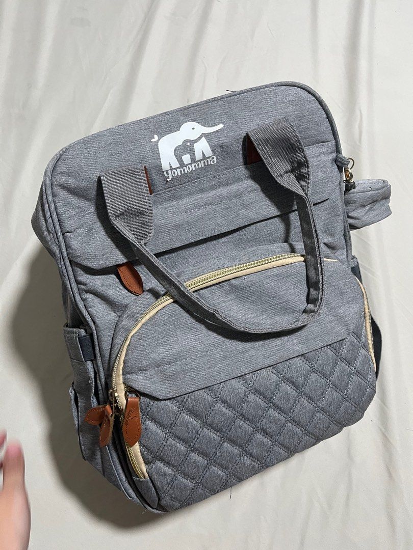 Yomomma Diaper Backpack Bag (Category: Diaper Bags & Wetbags) located in San Fernando. Submitted by akcd12 (Listing ID 1405059627, Image 1). Description: - Spacious main compartment - Multiple pockets for organization - Front quilted pocket - Side pockets - Detachable pouch - USB charging port - Includes changing pad - Stroller straps - Stylish gray with brown accents .