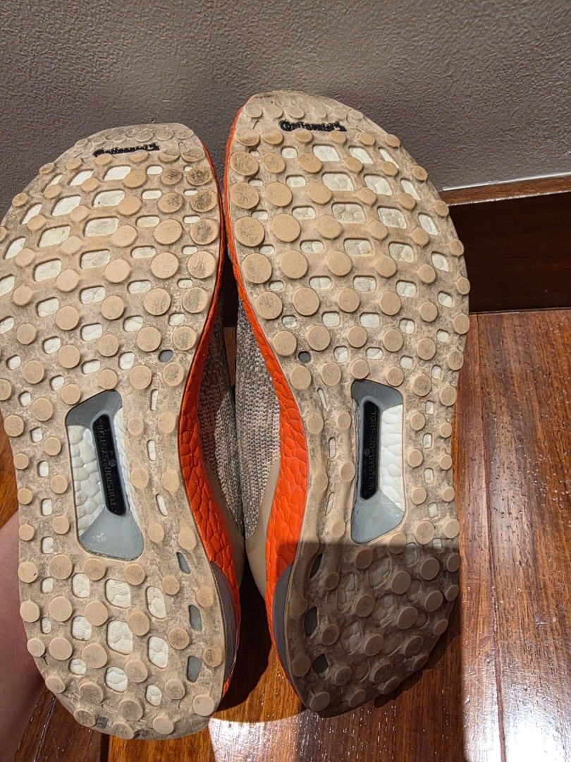 Adidas Ultraboost Sneakers (Category: Sneakers) located in Pasig City. Submitted by vthing (Listing ID 1401867262, Image 3). Description: Adidas Ultraboost sneakers with a grey and orange color scheme. Features the Adidas logo on the side. The shoes have grey laces and a knitted upper. The soles are orange and the bottom of the shoes have a Continental sole..