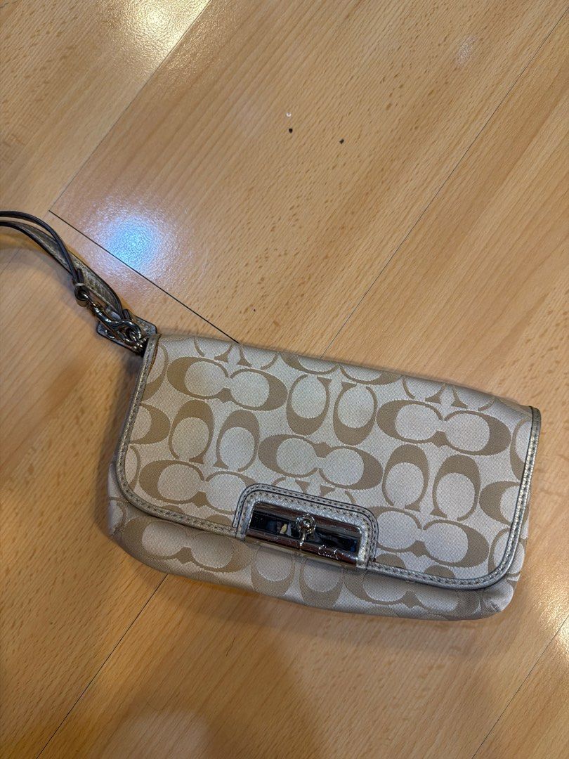 Coach Signature Clutch (Category: Luxury Bags & Wallets) located in Quezon City. Submitted by mademoiselle333 (Listing ID 1401782079, Image 2). Description: - Coach signature clutch - Includes wrist strap - Silver-tone clasp closure - Repeating Coach logo pattern (light beige) - Silver trim on edges.