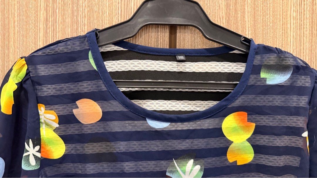 Floral Print Navy Blue Blouse (Category: Blouses) located in Taguig. Submitted by rizacarza (Listing ID 1401900214, Image 3). Description: Navy blue blouse with a floral print design. Features a round neckline and short sleeves. The blouse has a striped pattern on the front and back. There is a visible tear at the bottom hem. The blouse has a layered design with a white and black striped underlayer..