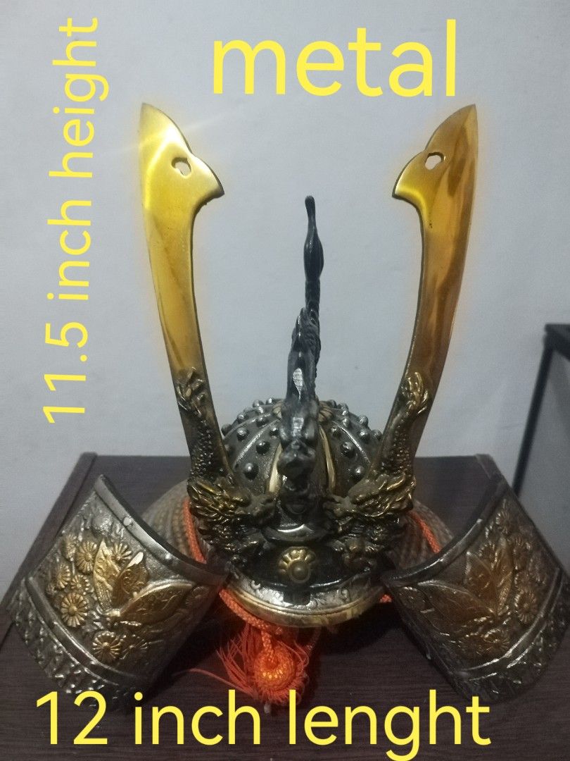 Metal Samurai Helmet - 12 inch Length (Category: Vintage Collectibles) located in San Rafael. Submitted by jflshoppe1989 (Listing ID 1401718564, Image 1). Description: Metal samurai helmet features a detailed design with golden accents. It measures 12 inches in length and 11.5 inches in height. The helmet includes decorative elements and an orange tassel..