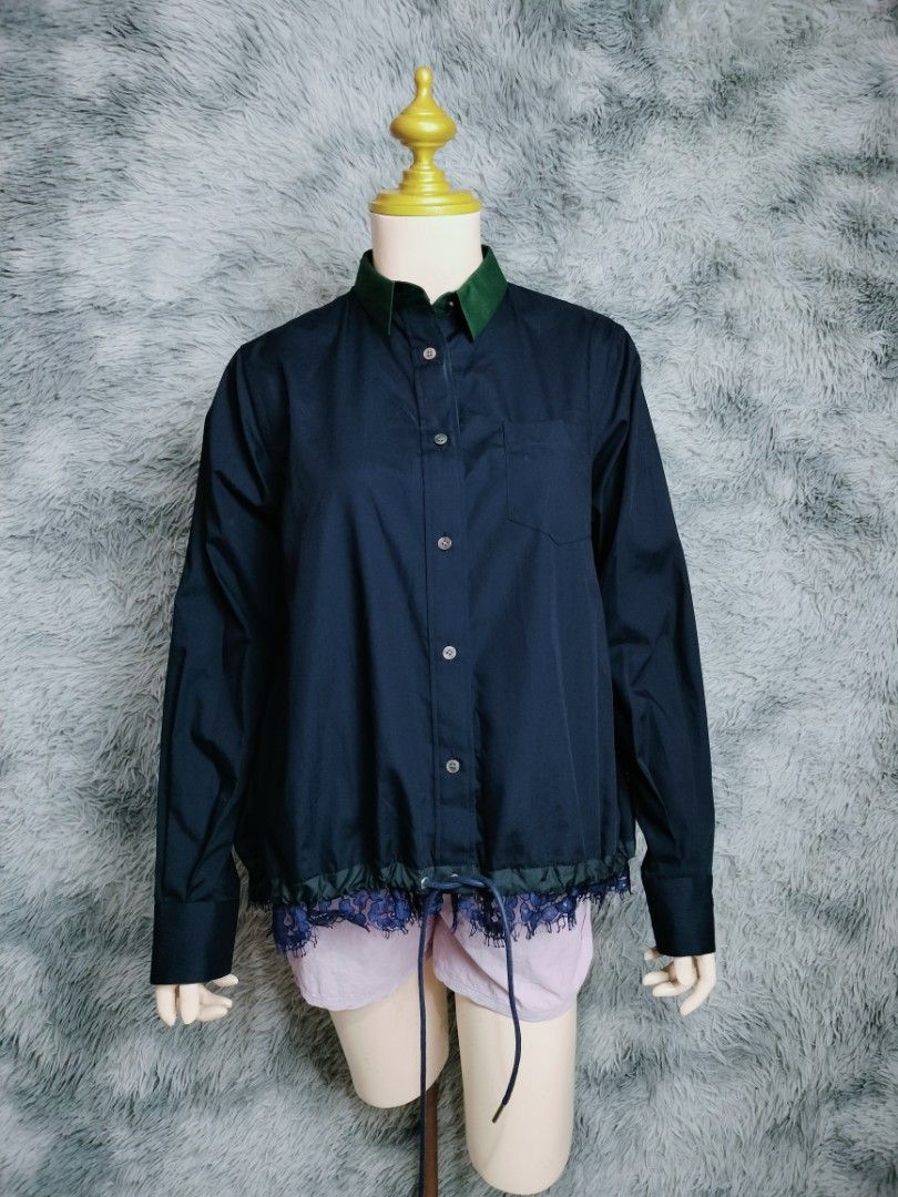 Sacai lace trim blouse navy (Category: Luxury Apparel) located in Rosales. Submitted by simplebyx.ph (Listing ID 1401850150, Image 1). Description: Navy shirt from Sacai with a green collar and lace detailing at the hem. Features a button-down front, a chest pocket, and long sleeves. The shirt has a drawstring at the waist. The tag indicates the shirt is made in Japan with a blend of polyester, cotton, rayon, and nylon. Sacai lace trim blouse nav