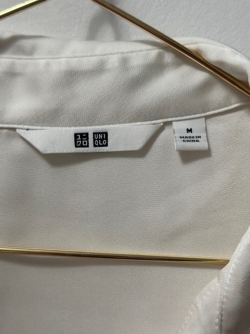 Uniqlo White Satin Blouse - Size M (Category: Blouses) located in Quezon City. Submitted by izha30 (Listing ID 1401894823, Image 2). Description: White satin blouse from Uniqlo, size M. Features long sleeves and button-down closure. Made in China. There are some small holes on the left sleeve. The blouse has a classic, elegant design, suitable for various occasions..