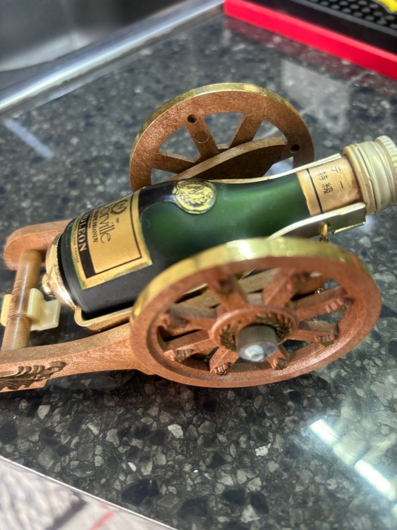 Dorville cannon mini liquor (Category: Vintage Collectibles) located in Manila. Submitted by jojopherna60447 (Listing ID 1405344356, Image 3). Description: - Miniature L. Dorville Napoleon cognac bottle. - Presented in a decorative cannon-shaped holder. - Bottle: Green glass with a gold label. - Cannon: Made of wood and brass. - Features detailed wheels and accents. - Bottle is secured within the cannon. - Label indicates 'Pure Grape Brandy'..