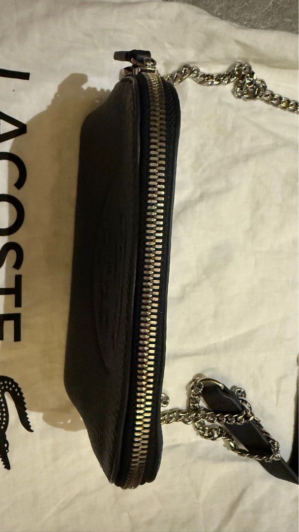 Lacoste Black Leather Crossbody Bag (Category: Cross-body Bags) located in Dumaguete. Submitted by pinksia36 (Listing ID 1405327427, Image 3). Description: - Lacoste black leather crossbody bag - Silver chain strap - Secure zip closure - Embossed Lacoste logo - Includes dust bag - Interior with small pocket.