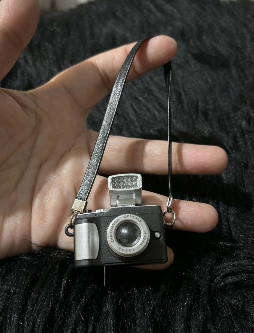 Miniature Camera with Strap (with light & sound) (Category: Cameras) located in Paranaque City. Submitted by dallecloset_ii (Listing ID 1405223871, Image 1). Description: Miniature black and silver camera with strap. Features a flash and "ZHONGYANG OPTICALS" lens. Perfect for collectors or display. working po yung flash & sound nya.