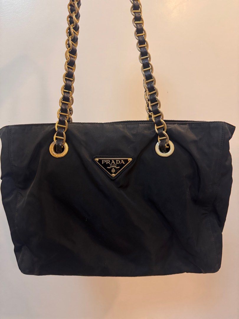 Prada Black Nylon Tote Bag with Chain Straps (Category: Luxury Bags & Wallets) located in Manila. Submitted by kjbsb_041 (Listing ID 1405164094, Image 1). Description: - Authentic Prada tote bag - Black nylon exterior - Gold-tone chain straps with leather detailing - Prada logo on the front - Zipper closure - Tote style With minimal Flaws on the exterior. No other inclusions. Location: Taytay Rizal. MOP: BDO, BPI only. .