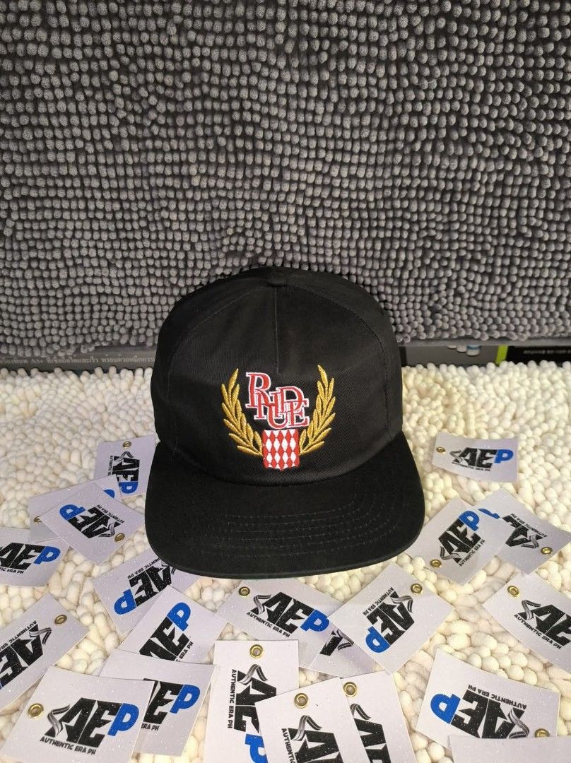 Rhude Caps made in USA (Category: Caps & Hats) located in San Jose del Monte. Submitted by authenticeraph (Listing ID 1405270092, Image 3). Description: - Black Rhude caps - Available designs: - White brand name - Green and gold logo - Red and gold emblem - Flat-brimmed.