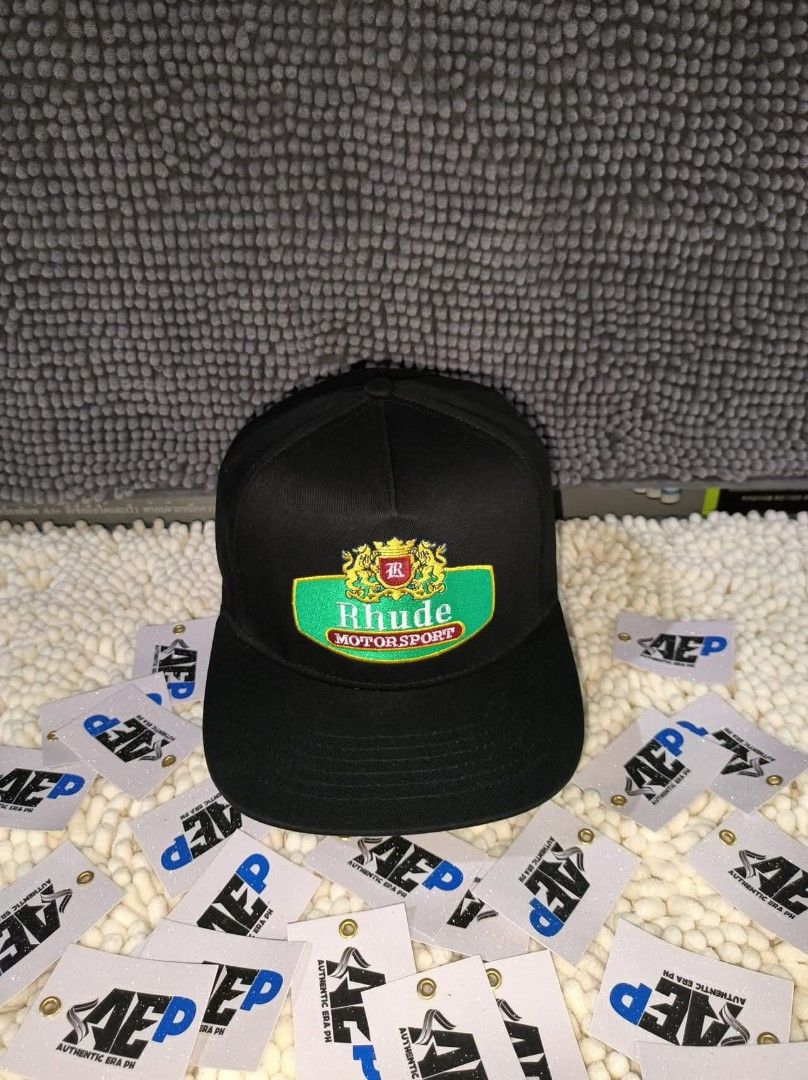 Rhude Caps made in USA (Category: Caps & Hats) located in San Jose del Monte. Submitted by authenticeraph (Listing ID 1405270092, Image 2). Description: - Black Rhude caps - Available designs: - White brand name - Green and gold logo - Red and gold emblem - Flat-brimmed.
