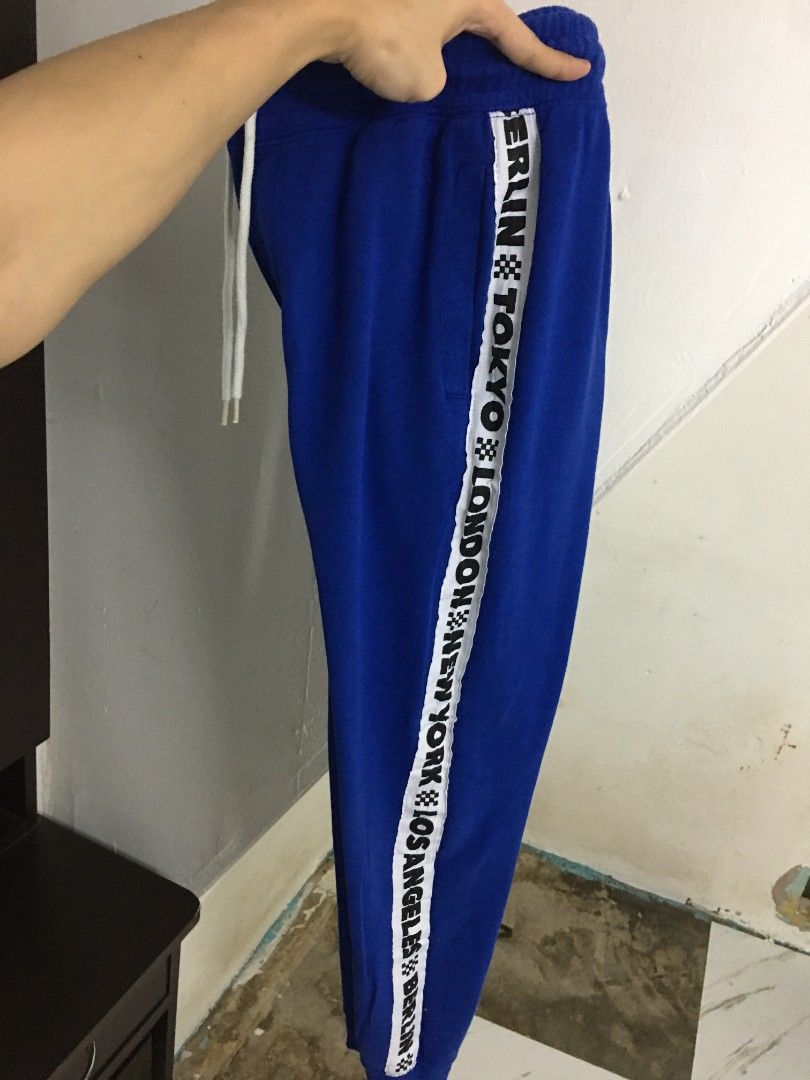 Cotton On Trippy Track Jogger Pants (Category: Joggers) located in Quezon City. Submitted by 2high2cry. (Listing ID 1405515436, Image 2). Description: - Cotton On Trippy Track jogger pants - Color: Blue with white accents - Size: XXS/PXP - Features: Drawstring waist, relaxed fit - Design: White band with city names (Berlin, Tokyo, London, New York, Los Angeles).