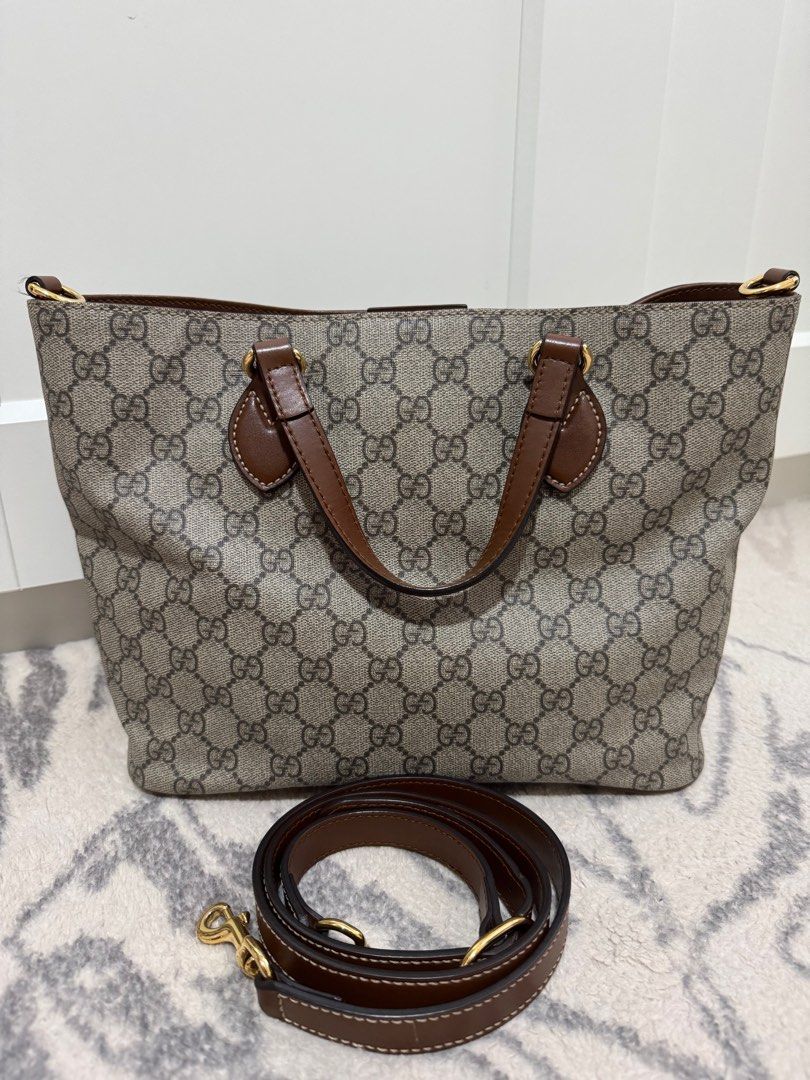Gucci GG Supreme Small Tote Bag (Category: Luxury Bags & Wallets) located in Quezon City. Submitted by preloveditemsbyc (Listing ID 1405421911, Image 3). Description: This bag is crafted of Gucci GG monogram coated canvas. It features brown leather top handles, magnetic top closure and an optional shoulder strap with gold-tone hardware. The top opens to a suede interior with one zipper pocket and two patch pockets. Length: 11” Height: 8.75” Width