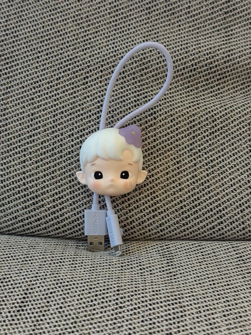 POP MART HACIPUPU The Constellation Series data cable. (Category: Chargers & Cables) located in Quezon City. Submitted by mikeepreloveditems (Listing ID 1405413133, Image 1). Description: - Adorable doll head design - USB and lightning connectors - White color with a purple bow - Features a loop for easy carrying - Unique and functional accessory.