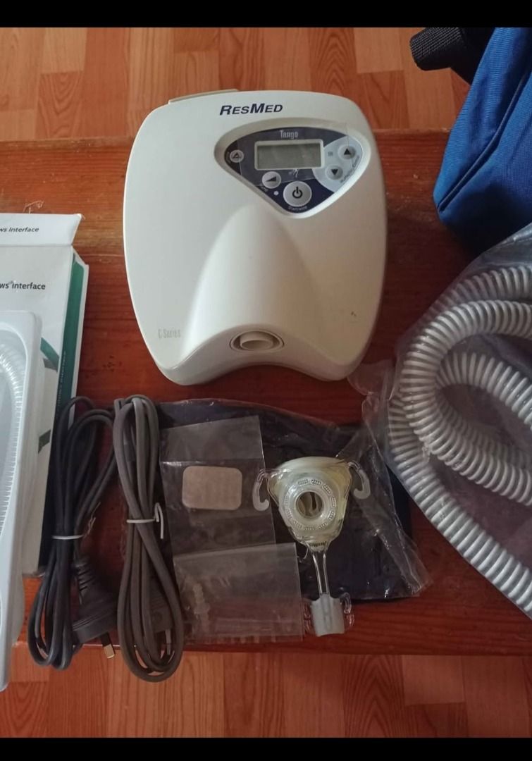 ResResMed Tango CPAP Machine with Accessories (Category: Medical Supplies & Tools) located in Baguio. Submitted by sibvirgy40652 (Listing ID 1405375588, Image 2). Description: ResMed Trilage CPAP machine with various accessories, including a nasal pillow interface, tubing, power cables, and a carrying bag. The machine has a digital display and control buttons. The included bag is blue with the ResMed logo. Additional accessories are also included
