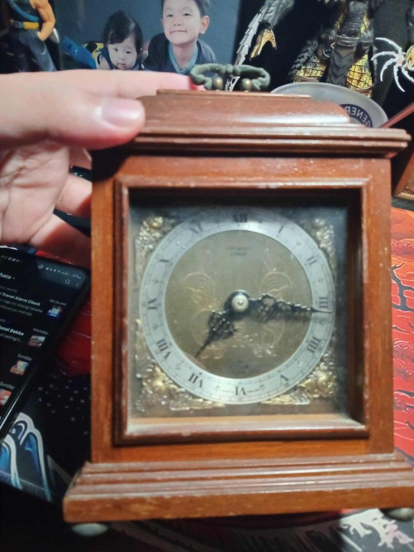 Vintage Wooden Elliot Clock (Category: Clocks) located in Taguig. Submitted by ashicollection (Listing ID 1405707292, Image 1). Description: - Vintage wooden clock - Gold-colored clock face with Roman numerals - Wooden frame - Winding mechanism marked "Made in England" - Features a handle - Decorative elements on clock face.