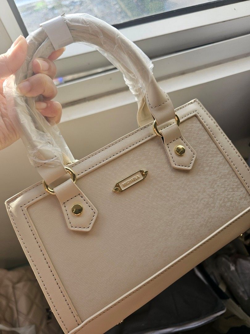 Michaela brand new Handbag (Category: Purses & Pouches) located in Makati City. Submitted by kathsclosetdeclutter (Listing ID 1405879958, Image 2). Description: discounted from mall price - Elegant top-handle handbag - Rectangular shape with structured design - Features gold-colored hardware - Secure zipper closure - Handle wrapped in protective plastic - Includes brand tag, dust bag and plastic - Gifted but i have too many bags already.