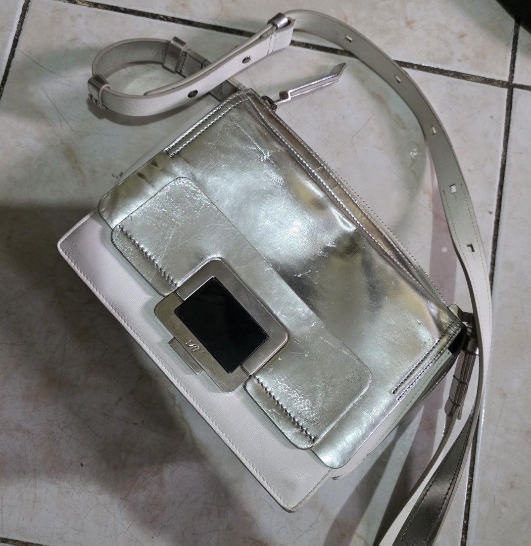 Roger Vivier Paris Silver Shoulder Bag (Category: Luxury Bags & Wallets) located in Quezon City. Submitted by phoejay (Listing ID 1405726676, Image 2). Description: - Roger Vivier Paris shoulder bag - Silver metallic finish - White leather base - Silver-tone shoulder strap - Rectangular clasp - Black leather interior - Roger Vivier Paris logo - Zipper closure.