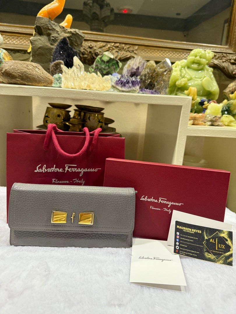 Salvatore Ferragamo Grey Leather Wallet (Category: Luxury Bags & Wallets) located in Taytay. Submitted by allluxbymaureenreyes7 (Listing ID 1405749292, Image 1). Description: - Authentic Salvatore Ferragamo wallet - Grey leather exterior - Gold-tone clasp and hardware - Includes original box, shopping bag, and authenticity card - Multiple card slots and zippered compartment inside - Made in Italy.