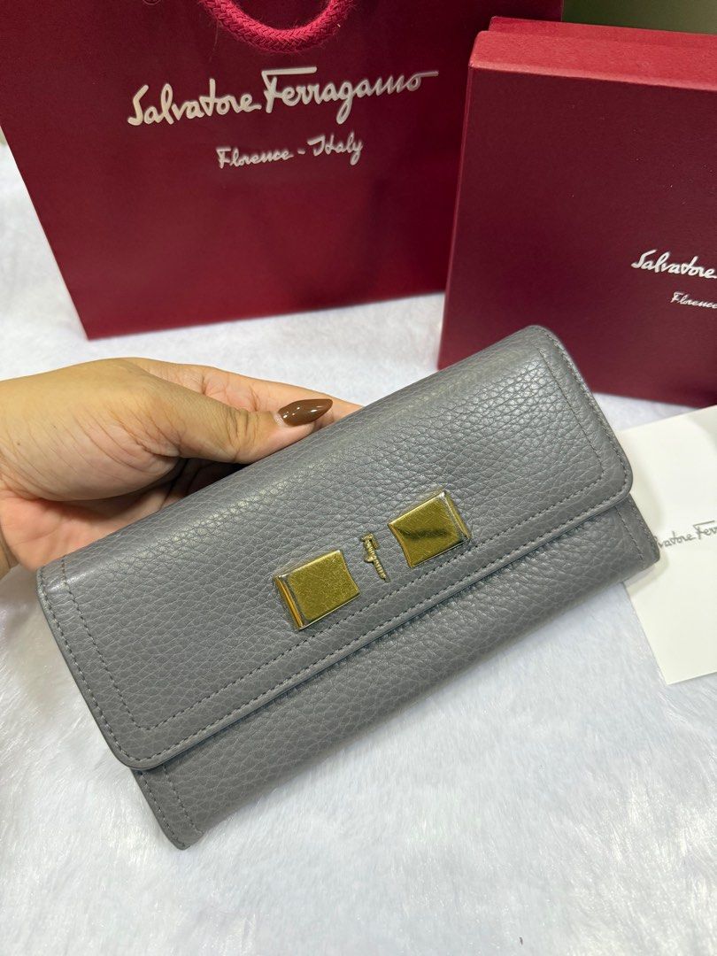Salvatore Ferragamo Grey Leather Wallet (Category: Luxury Bags & Wallets) located in Taytay. Submitted by allluxbymaureenreyes7 (Listing ID 1405749292, Image 2). Description: - Authentic Salvatore Ferragamo wallet - Grey leather exterior - Gold-tone clasp and hardware - Includes original box, shopping bag, and authenticity card - Multiple card slots and zippered compartment inside - Made in Italy.