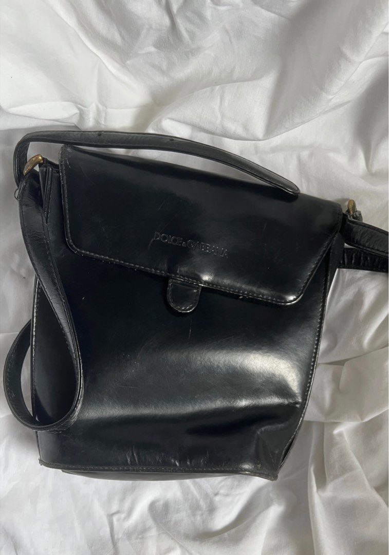 Dolce & Gabbana Black Shoulder Bag (Category: Luxury Bags & Wallets) located in Quezon City. Submitted by hollyyybac25473 (Listing ID 1405988983, Image 1). Description: - Dolce & Gabbana shoulder bag - Black color - Flap closure with magnetic snap - Interior zippered pocket with Dolce & Gabbana label - Long strap for shoulder or crossbody wear - Gold-toned hardware Well used. Rusty metal buckles (can still be removed). Actual photos posted, pleas