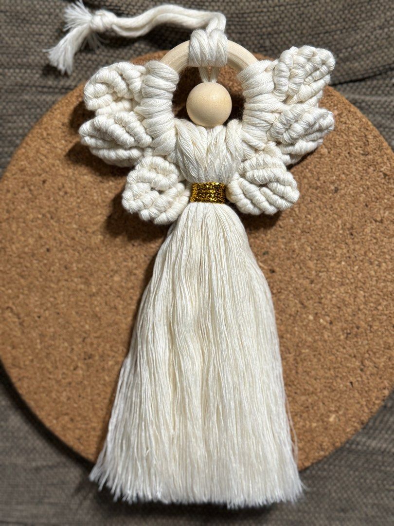 Macrame Angel Wall Hanging (Category: Wall Decor) located in Pasig City. Submitted by sinta_studio (Listing ID 1405912883, Image 1). Description: - Handmade macrame angel - Cream-colored design - Wooden bead head - Gold-colored accent - Includes a wooden ring - Approximately 7 inches in height.