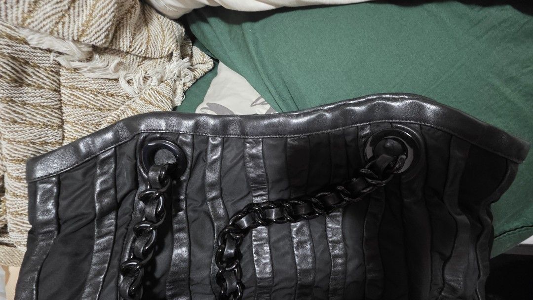 Prada Black Chain Tote Bag (Category: Luxury Bags & Wallets) located in Mandaluyong City. Submitted by snapitupgoods (Listing ID 1406015862, Image 3). Description: Black Prada tote bag with chain straps. Features a pleated design and a Prada logo on the front. The interior has a Prada logo lining. Includes a small leather tag attached to the chain. The bag has a zipper closure..