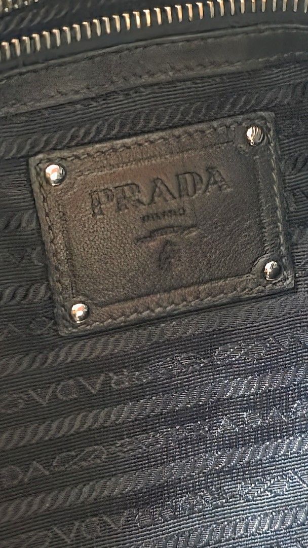 Prada Black Chain Tote Bag (Category: Luxury Bags & Wallets) located in Mandaluyong City. Submitted by snapitupgoods (Listing ID 1406015862, Image 2). Description: Black Prada tote bag with chain straps. Features a pleated design and a Prada logo on the front. The interior has a Prada logo lining. Includes a small leather tag attached to the chain. The bag has a zipper closure..