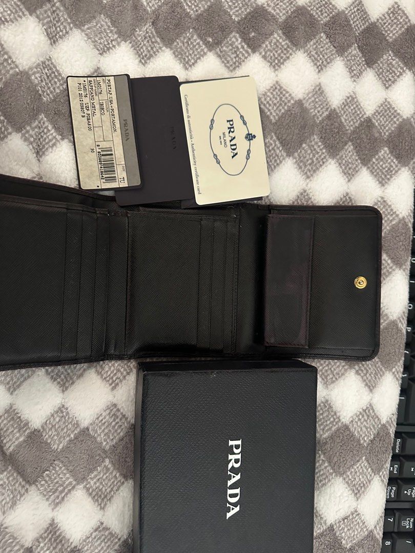 Prada Saffiano Metal Tri-Fold Wallet (Category: Luxury Bags & Wallets) located in Marilao. Submitted by kikaypena (Listing ID 1405970831, Image 3). Description: - Authentic Prada tri-fold wallet - Black Saffiano leather - Includes original box, authenticity cards, and product tag - Coin compartment - Multiple card slots - Prada logo visible - Well-maintained -Recolored.
