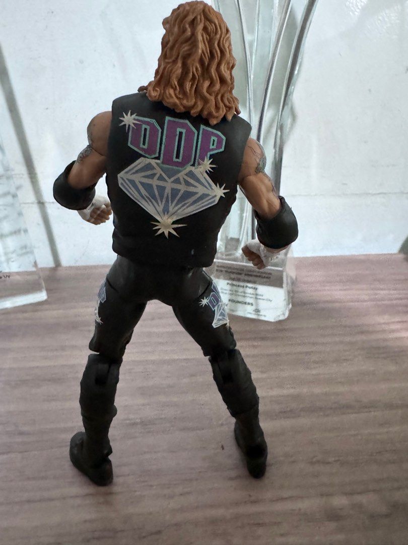DDP Diamond Dallas Page Action Figure (Category: Action & Battle Toys) located in Quezon City. Submitted by princesspatsy100 (Listing ID 1406232616, Image 3). Description: - Diamond Dallas Page (DDP) action figure. - Features DDP in black vest and pants. - Detailed tattoos on arms. - Includes DDP logo on the back. - Collectible item for wrestling fans. - Posed in a standing position..
