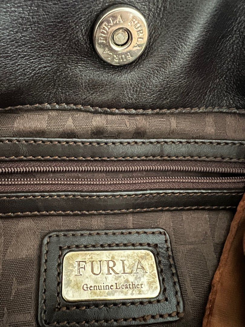 MUST GO!! FURLA Leather Handbag (Category: Luxury Bags & Wallets) located in Las Pinas. Submitted by sabs28 (Listing ID 1406158113, Image 2). Description: - Authentic Furla leather handbag - Dark brown exterior - Spacious interior with zippered and small pockets - Wrapped with a patterned scarf due to some tears in handles - Metal feet on the bottom - Furla logo visible inside and outside.