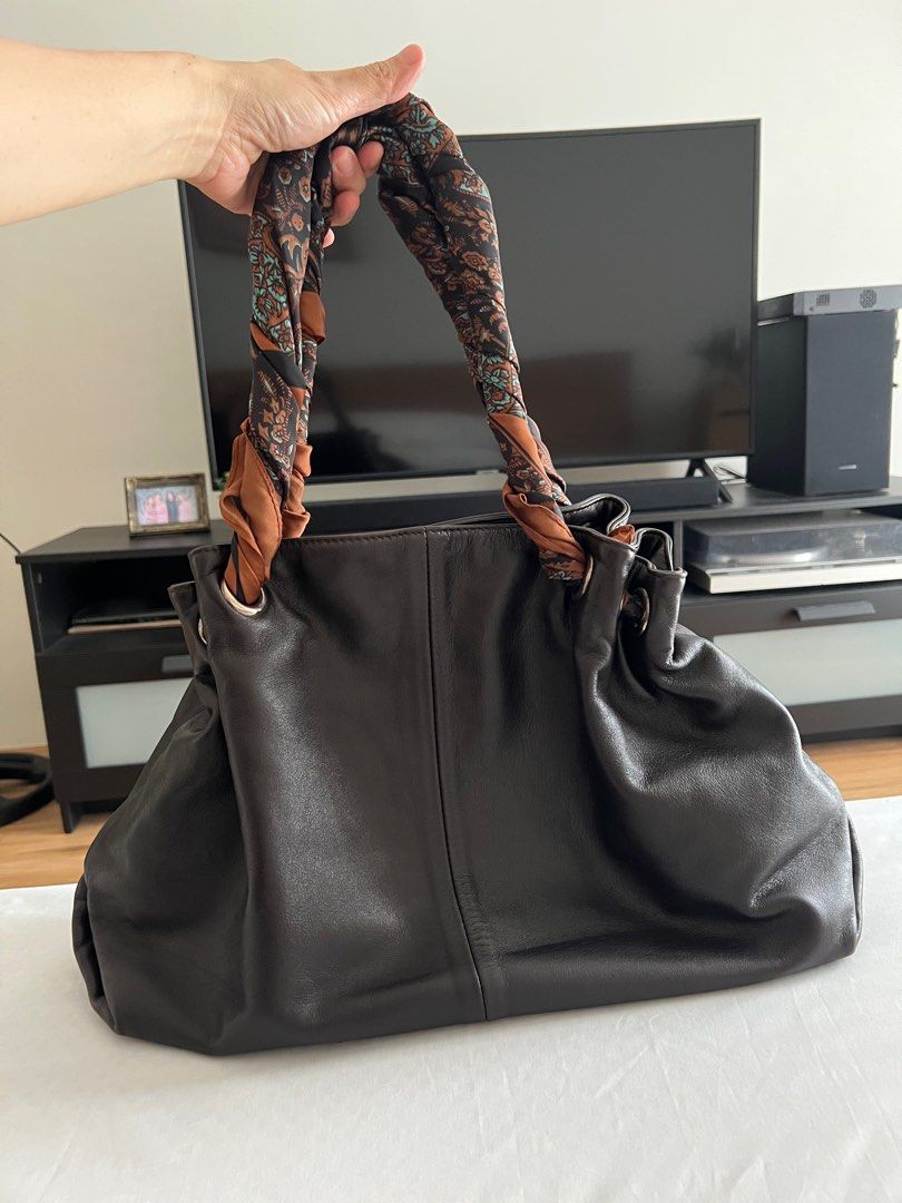 MUST GO!! FURLA Leather Handbag (Category: Luxury Bags & Wallets) located in Las Pinas. Submitted by sabs28 (Listing ID 1406158113, Image 3). Description: - Authentic Furla leather handbag - Dark brown exterior - Spacious interior with zippered and small pockets - Wrapped with a patterned scarf due to some tears in handles - Metal feet on the bottom - Furla logo visible inside and outside.