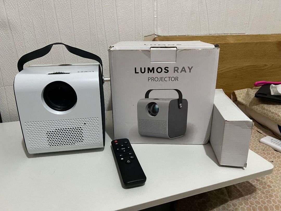 Lumos Ray Projector with Remote (Category: Projectors) located in Manila. Submitted by joannesq21171 (Listing ID 1406184826, Image 1). Description: - Lumos Ray projector with remote control - Includes original box - Features HDMI and USB ports - Remote control batteries included - Portable with a built-in handle - Stylish white and black design Issue: Missing battery cover on remote.