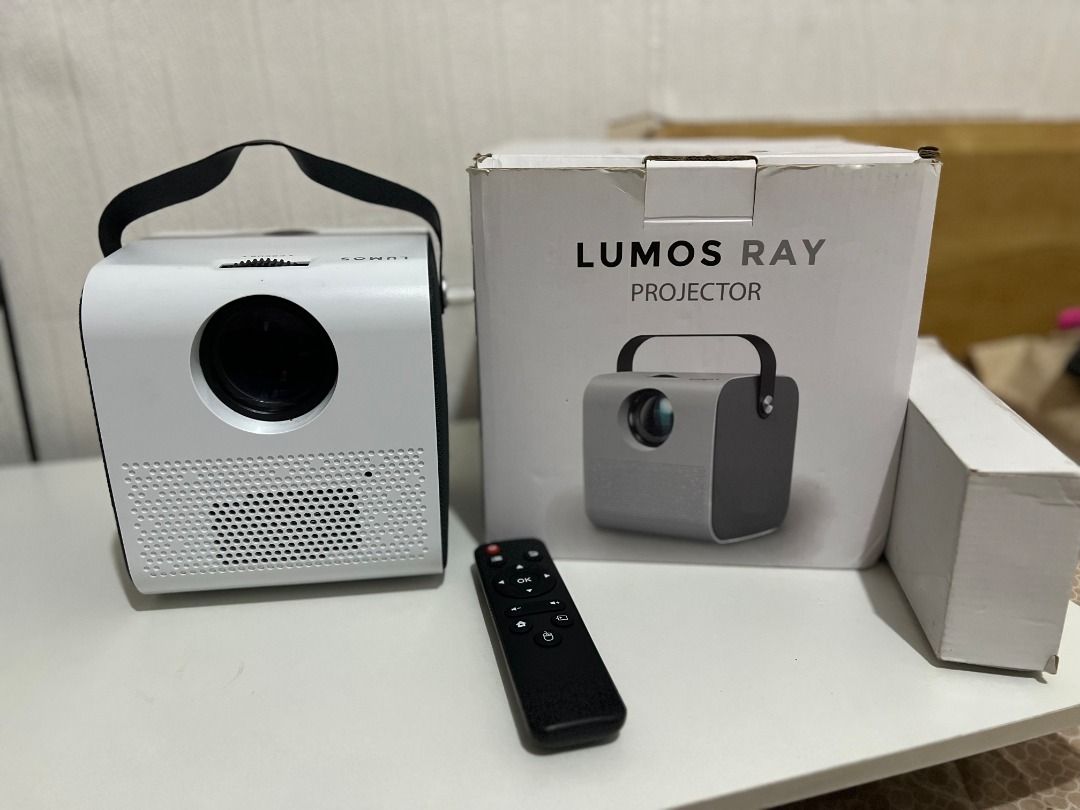 Lumos Ray Projector with Remote (Category: Projectors) located in Manila. Submitted by joannesq21171 (Listing ID 1406184826, Image 2). Description: - Lumos Ray projector with remote control - Includes original box - Features HDMI and USB ports - Remote control batteries included - Portable with a built-in handle - Stylish white and black design Issue: Missing battery cover on remote.