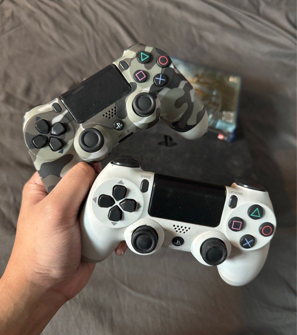 PS4 Slim 500gb with 2 controllers + 2 games (read description) (Category: PlayStation) located in Pasig City. Submitted by robbiseraphin (Listing ID 1406193185, Image 2). Description: - PlayStation 4 console (black) - Includes two controllers: one white, one camouflage - Comes with two game discs - Features HDMI, Ethernet, and other connection ports - Warranty void if seal is removed.