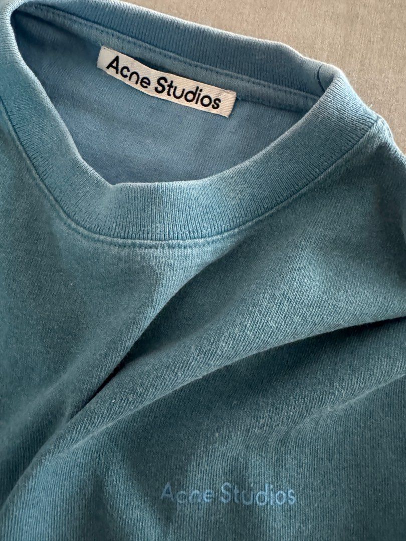 Acne Studios Oversized Blue Cotton T-shirt (Category: Tshirts & Polo Shirts ) located in Pasig City. Submitted by heattsupply (Listing ID 1406295983, Image 3). Description: Acne Studios T-shirt is made of 100% cotton. It features a light blue color and a crew neck. The Acne Studios logo is visible on the front and inside the collar. The tag indicates it was made in Portugal. Oversized fit Measurements: 24W x 29.