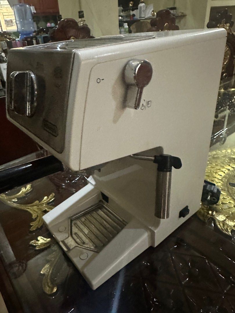 DeLonghi Espresso Machine (Category: Coffee Machines & Makers) located in Quezon City. Submitted by luxmamaqc (Listing ID 1406346340, Image 3). Description: DeLonghi espresso machine with a stainless steel and white finish. Features a steam wand and a dial for different coffee settings. Includes a portafilter holder. The power cord is included. The machine has a few signs of use..