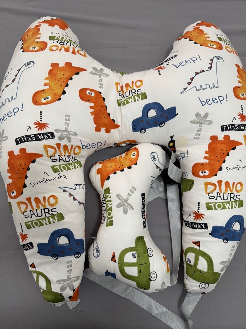 Dinosaur Print Pillow Car (Category: Car Seats) located in Pasay City. Submitted by szepter (Listing ID 1406321027, Image 1). Description: - Fun dinosaur and car print design - Curved design for comfortable breastfeeding support - Includes a smaller, detachable pillow for added support - Features straps for secure positioning - Soft fabric and colorful design.