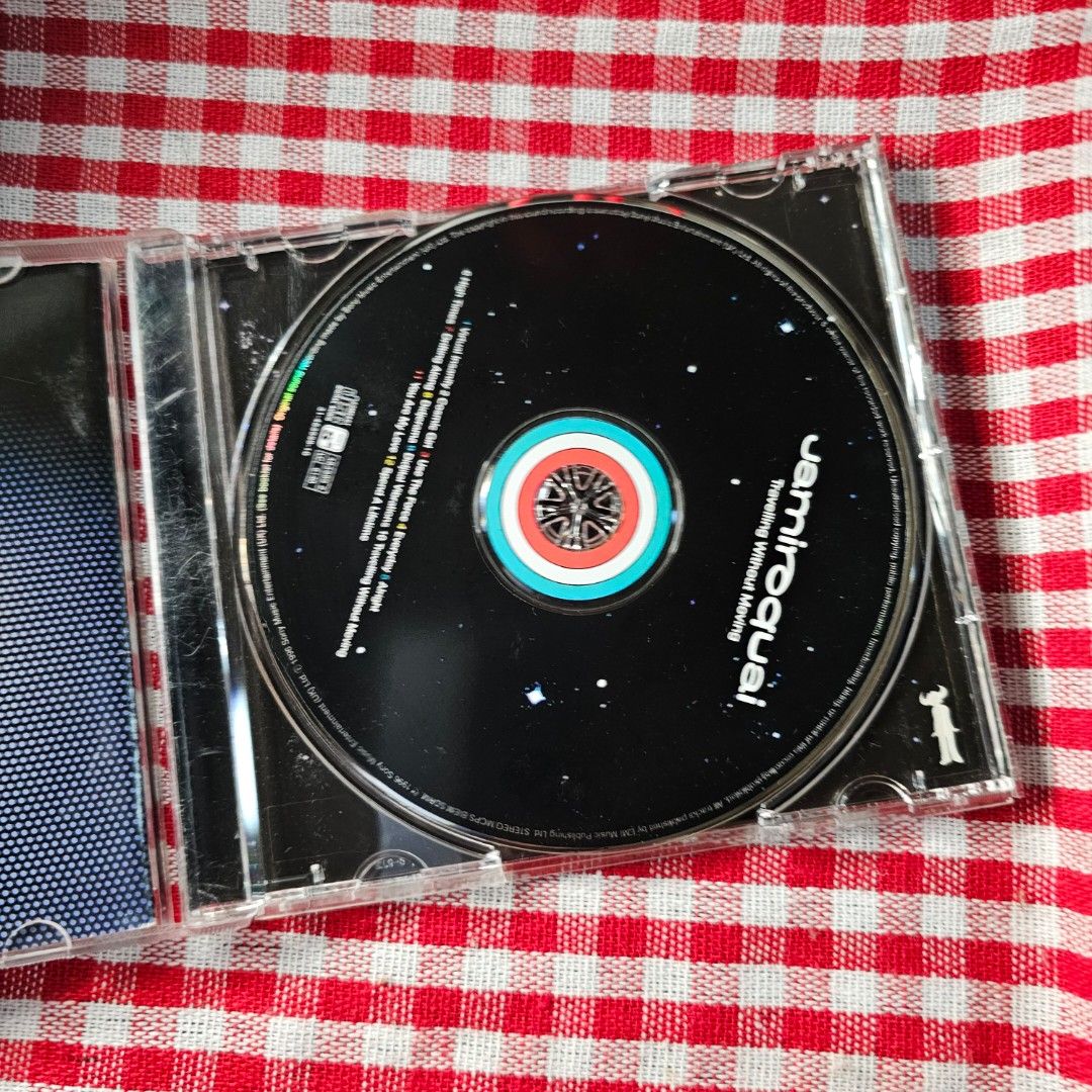 Jamiroquai Travelling Without Moving CD (Category: CDs & DVDs) located in Quezon City. Submitted by serefrenpaz (Listing ID 1406430055, Image 2). Description: Jamiroquai's album "Travelling Without Moving" on CD. Includes the CD, the jewel case, and the album booklet with lyrics. The CD features the iconic Jamiroquai logo and album art. The back of the case lists the tracklist. A sticker is present on the front of the case..