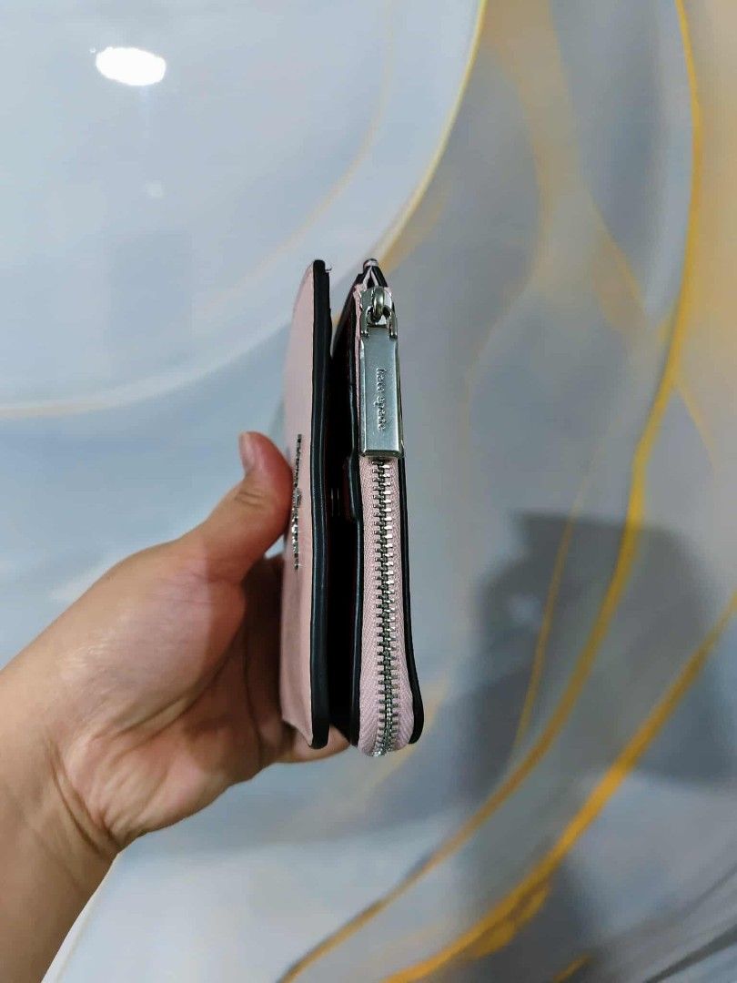 Kate Spade New York Zip Around Wallet (Category: Wallets & Card holders) located in Manila. Submitted by oliviavaleria (Listing ID 1406385929, Image 3). Description: - Kate Spade wallet - Zip-around closure - Light pink exterior - Multiple card slots - Coin compartment - Deep red interior lining - Silver zipper - Kate Spade logo on front.