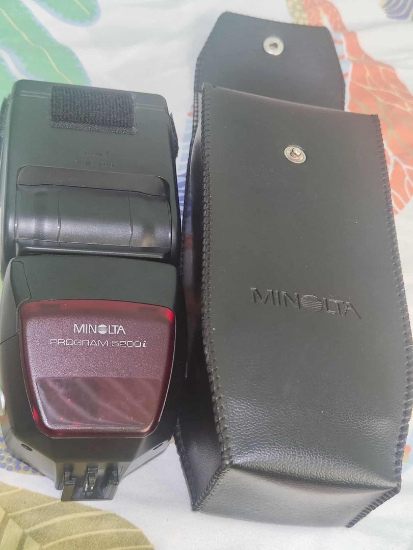 Minolta Program 5200i Flash (working) (Category: Cameras) located in Manila. Submitted by butihingmakinarya (Listing ID 1406330479, Image 3). Description: Minolta Program 5200i flash unit. Includes the flash unit and a protective case. The flash has an LCD screen displaying settings. The flash is turned on and set to TTL mode. The flash head has a zoom function. The battery compartment is visible..
