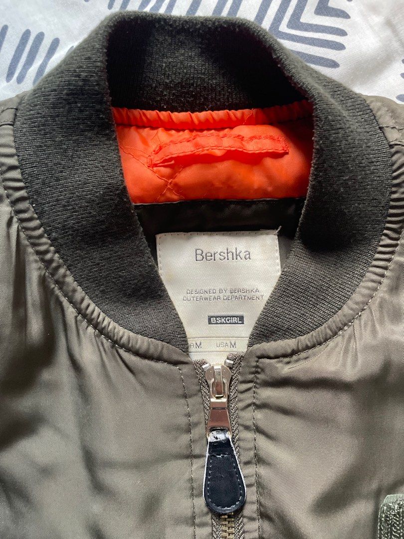 Bershka Bomber Jacket with Patches (Category: Coats, Jackets and Outerwear) located in Las Pinas. Submitted by bmtl_ (Listing ID 1406554671, Image 3). Description: Stylish Bershka bomber jacket in olive green. Features multiple patches, a zip closure, and ribbed cuffs and hem. The jacket has an orange lining. Size M. Perfect for adding a touch of edge to any outfit. RFS: Decluttering Negotiable.