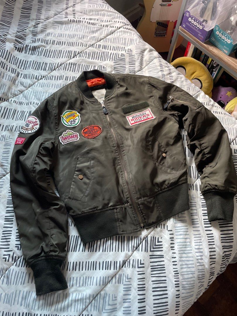 Bershka Bomber Jacket with Patches (Category: Coats, Jackets and Outerwear) located in Las Pinas. Submitted by bmtl_ (Listing ID 1406554671, Image 1). Description: Stylish Bershka bomber jacket in olive green. Features multiple patches, a zip closure, and ribbed cuffs and hem. The jacket has an orange lining. Size M. Perfect for adding a touch of edge to any outfit. RFS: Decluttering Negotiable.