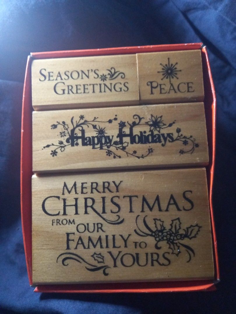 Christmas Holiday Rubber Stamps Set (Category: Craft Supplies & Tools) located in Manila. Submitted by firejoule (Listing ID 1406585219, Image 1). Description: - Christmas stamp set - Includes 4 wooden stamps - Features holiday greetings: "Season's Greetings", "Peace", "Happy Holidays", "Merry Christmas from our family to yours" - Comes in a red storage box - Perfect for crafts and cards.