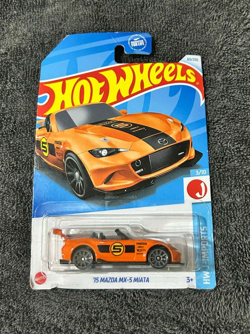 Hot Wheels '15 Mazda MX-5 Miata (Category: Vehicle & Diecast Models) located in Manila. Submitted by rufustilinskitwo (Listing ID 1406580033, Image 1). Description: - Hot Wheels '15 Mazda MX-5 Miata diecast car. - Orange body with black accents. - Features the number 5. - Part of the HW J-Imports series. - 3/10 model..